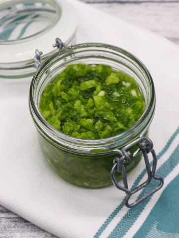 Fresh jalapeño relish in jar on green and white towel