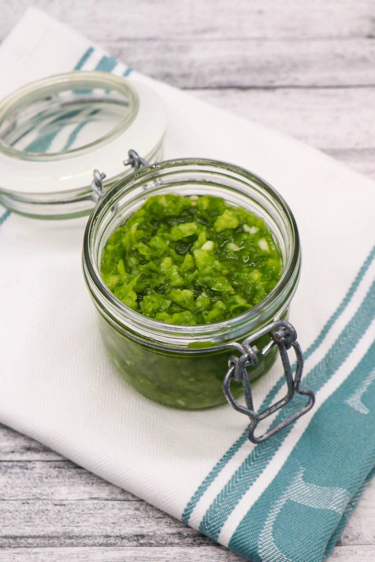 Fresh jalapeño relish in jar on green and white towel