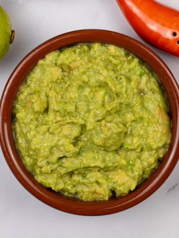 Guacamole in a terracotta serving dish.