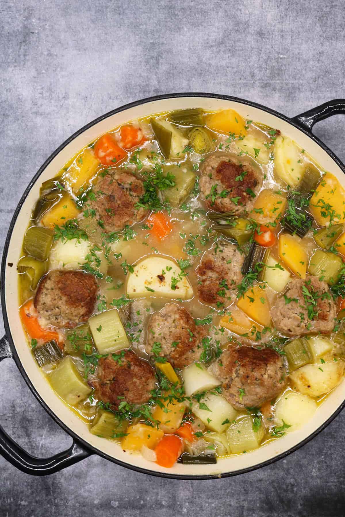 Lamb meatball cawl in a large round casserole.