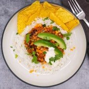 Mexican turkey chilli with rice, tortilla crisps, avocado, coriander and soured cream in bowl