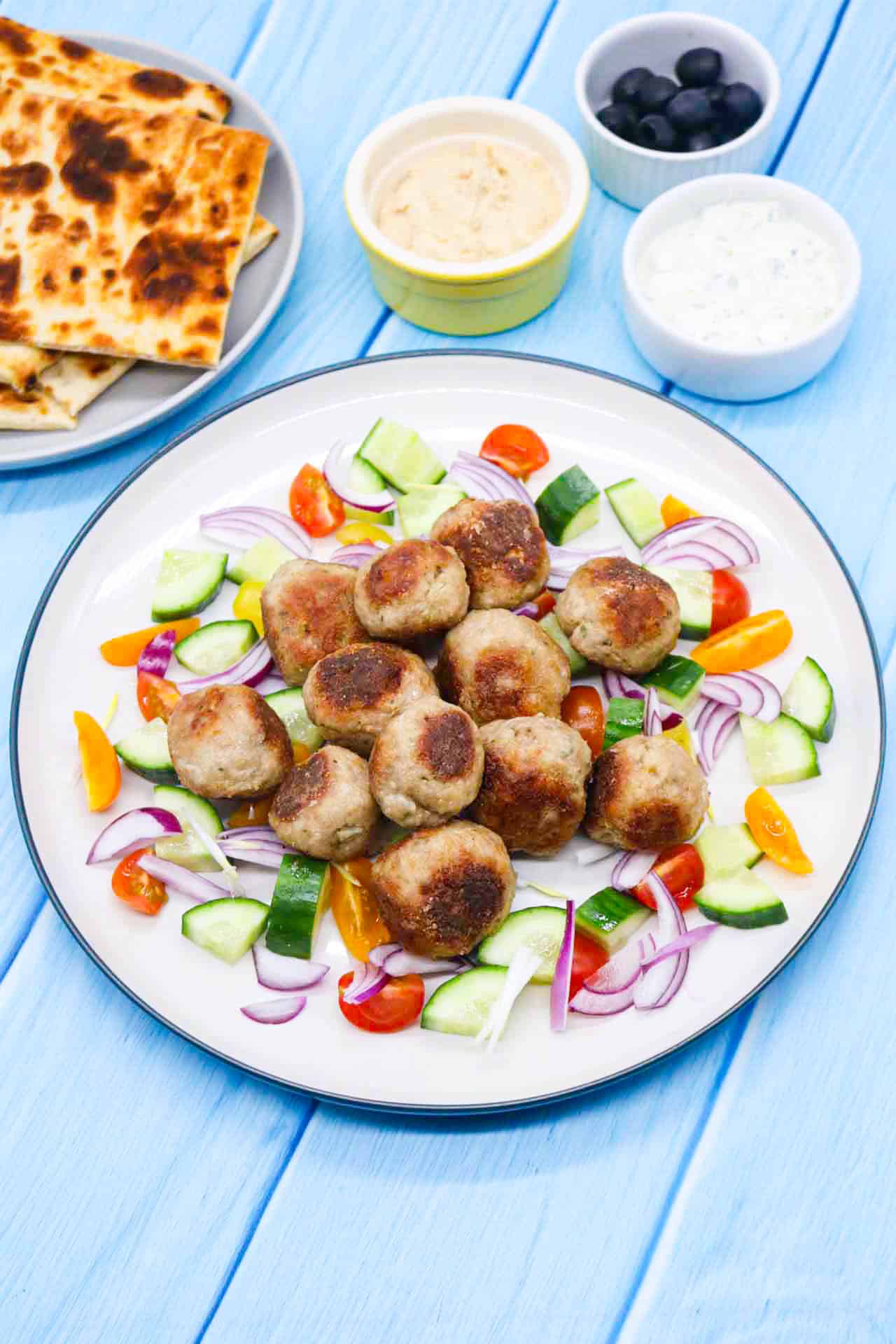Meze meatbals in plate with onion, cucumber and tomatoes.