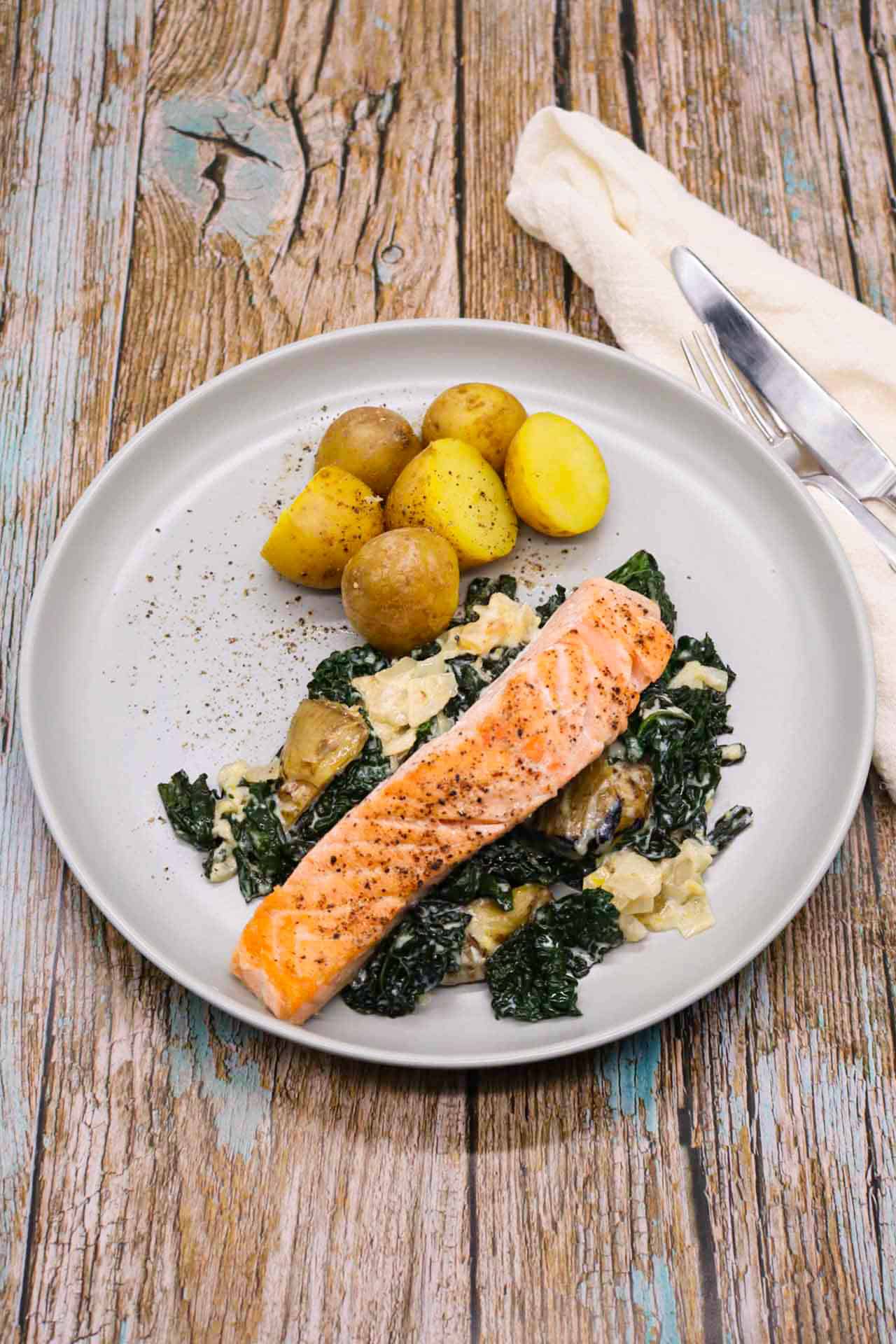 Salmon and creamy artichoke sauce with potatoes on grey plate