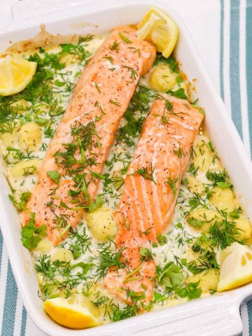 Salmon and gnocchi in rectangle serving dish with lemon wedges