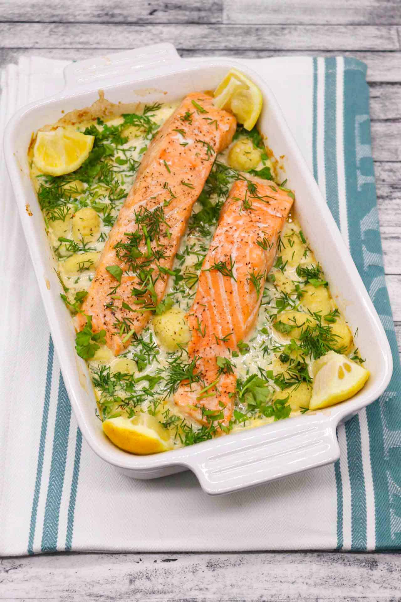 Salmon and gnocchi in rectangle serving dish with lemon wedges