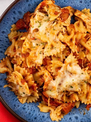 Close up of a portion of slow cooker chicken parmesan pasta in a blue patterned bowl.