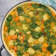Chunky veg stew with cheesy dumplings in a large round casserole.