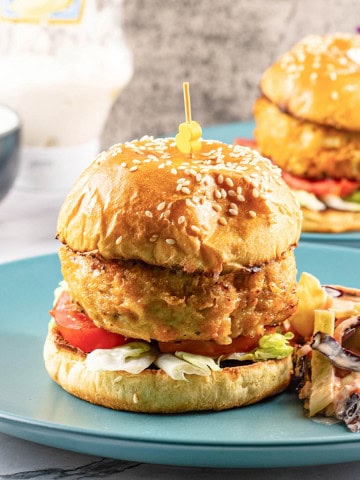 Buffalo turkey cheeseburger and coleslaw on a teal dinner plate.