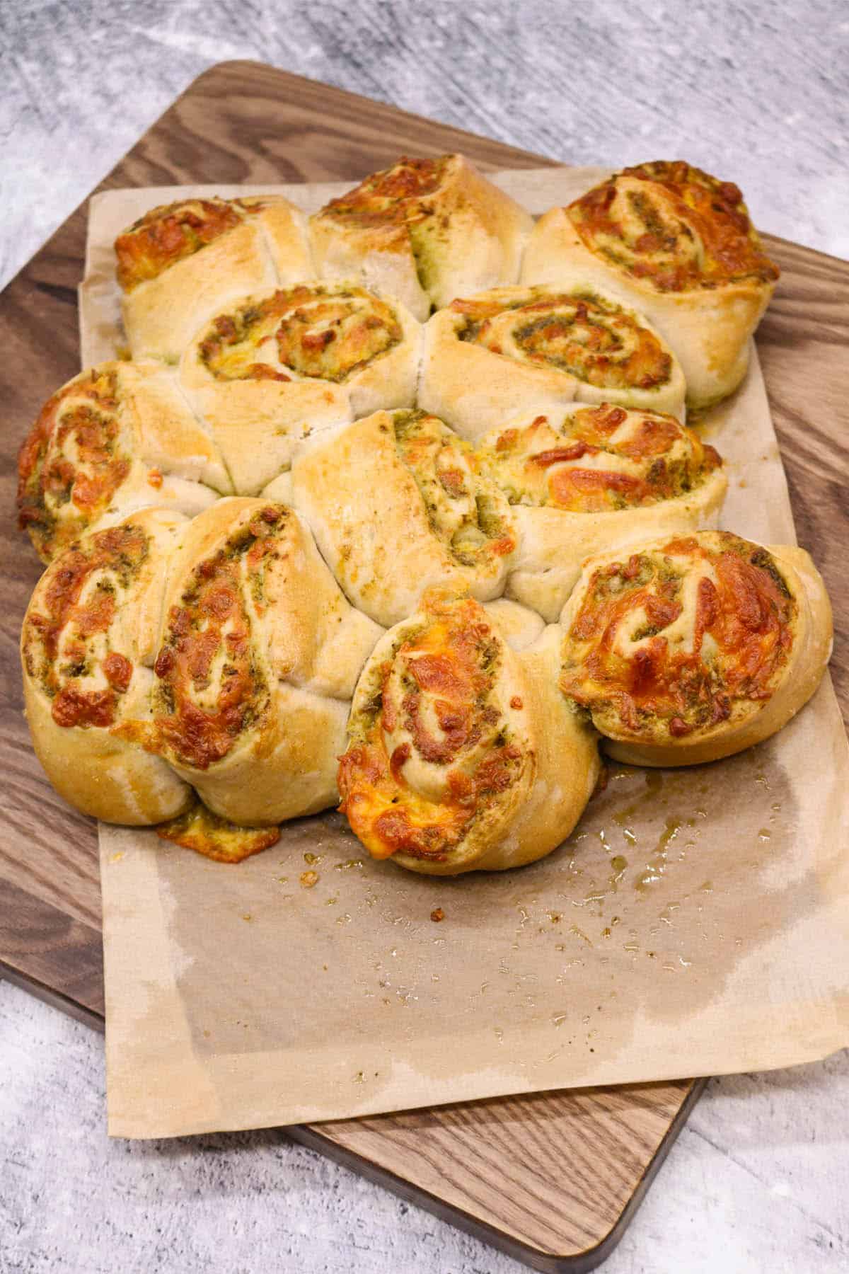 Cheese pesto swirls in baking paper on wooden board