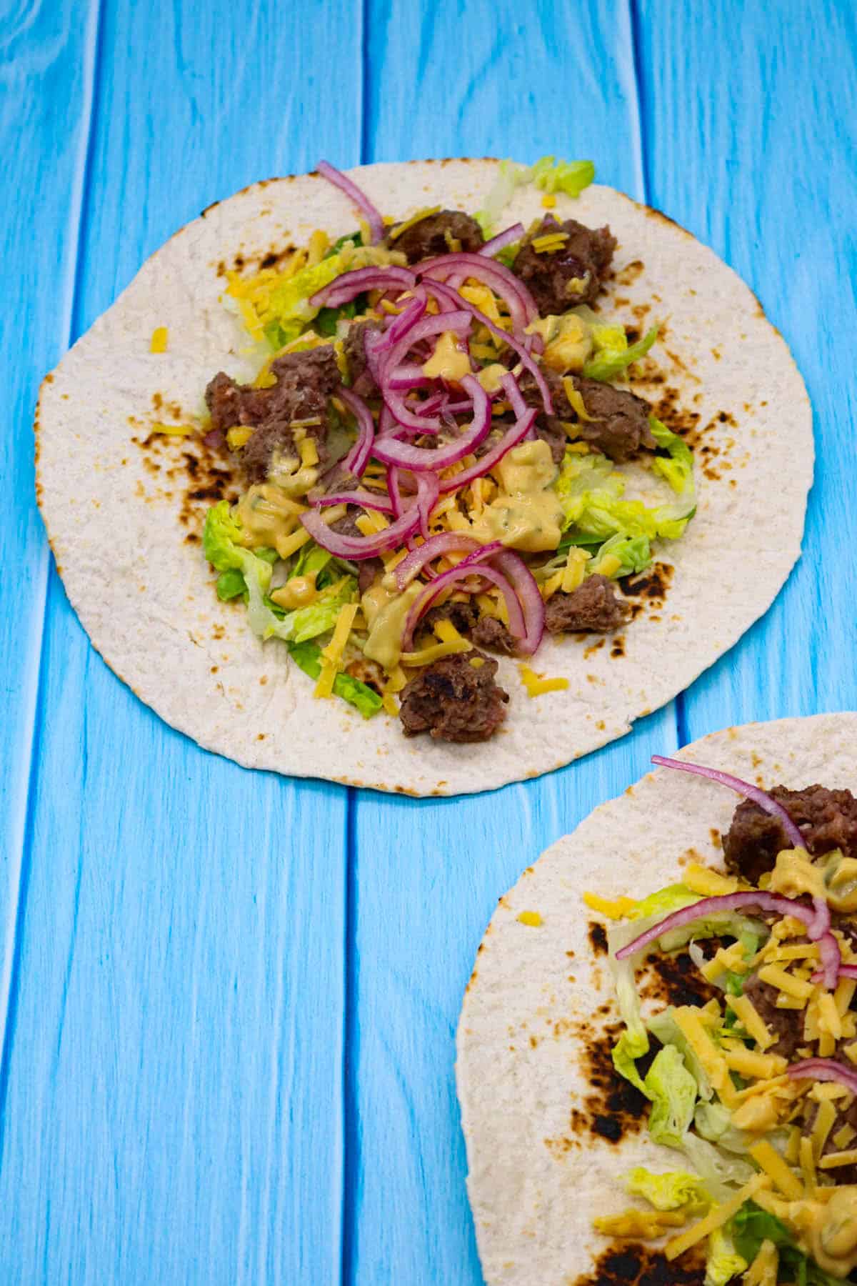 Cheeseburger tacos with red onion, cheese and lettuce