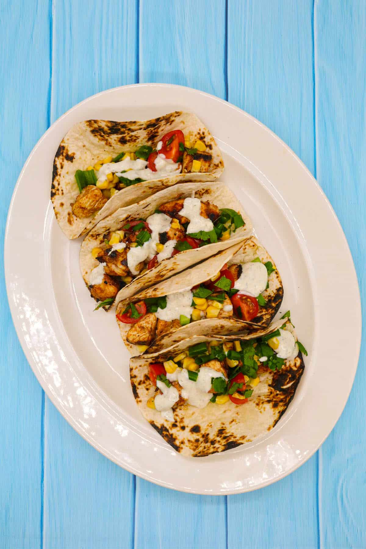 Chicken and corn in flour tortillas on white oval serving platter