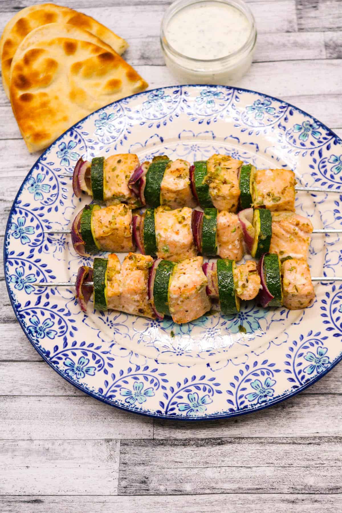 Mediterranean salmon kebabs on a blue and white plate