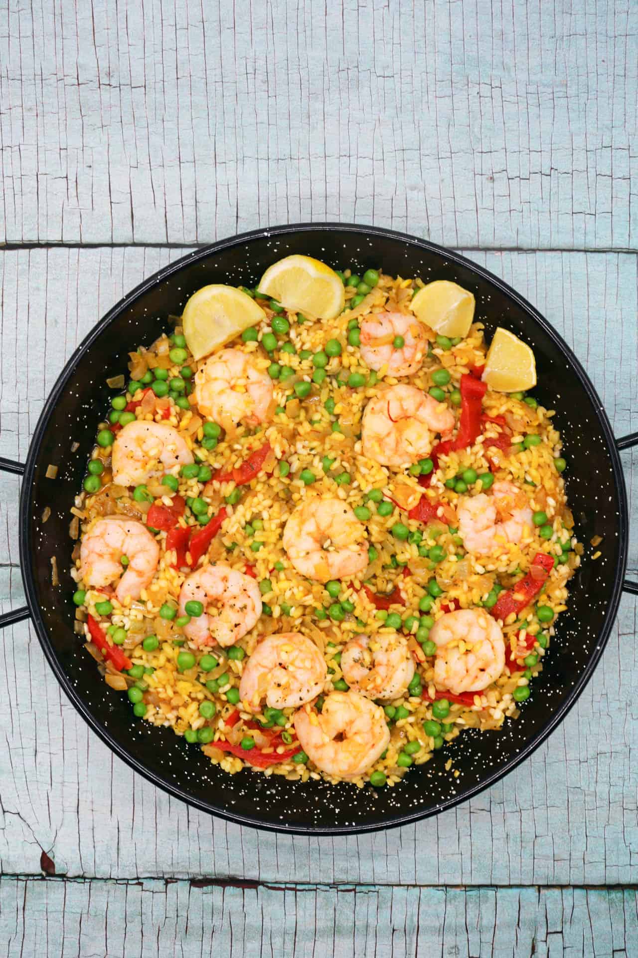 Prawn paella in paella pan with lemon wedges