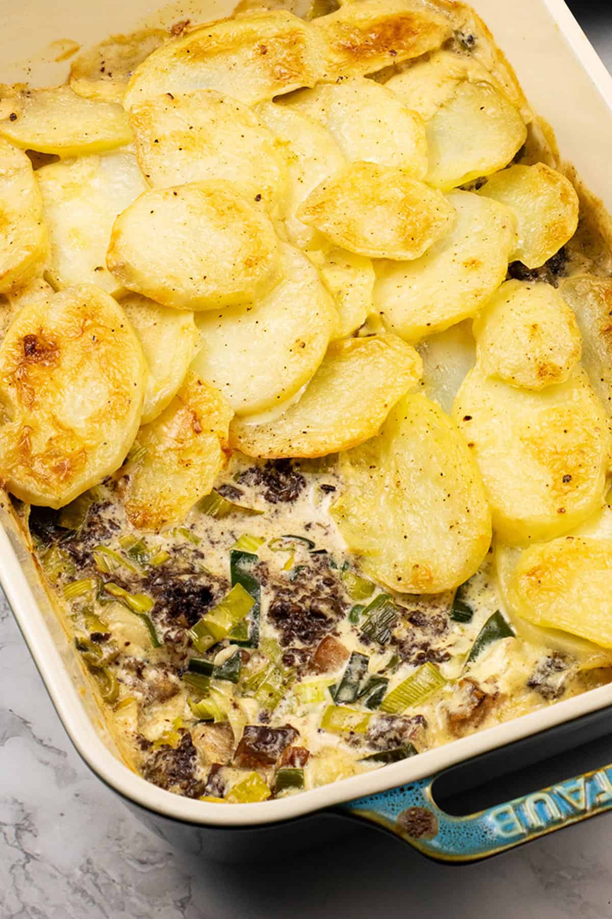 Close up of smoked haddock, black pudding and leek gratin in a rectangle Staub dish.