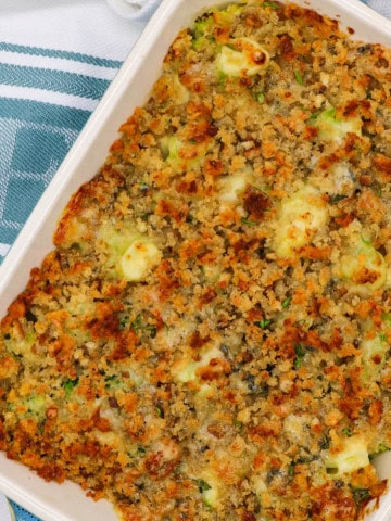 Broccoli and stilton crumble in a rectangle Staub oven dish sitting on a white and teal towel.