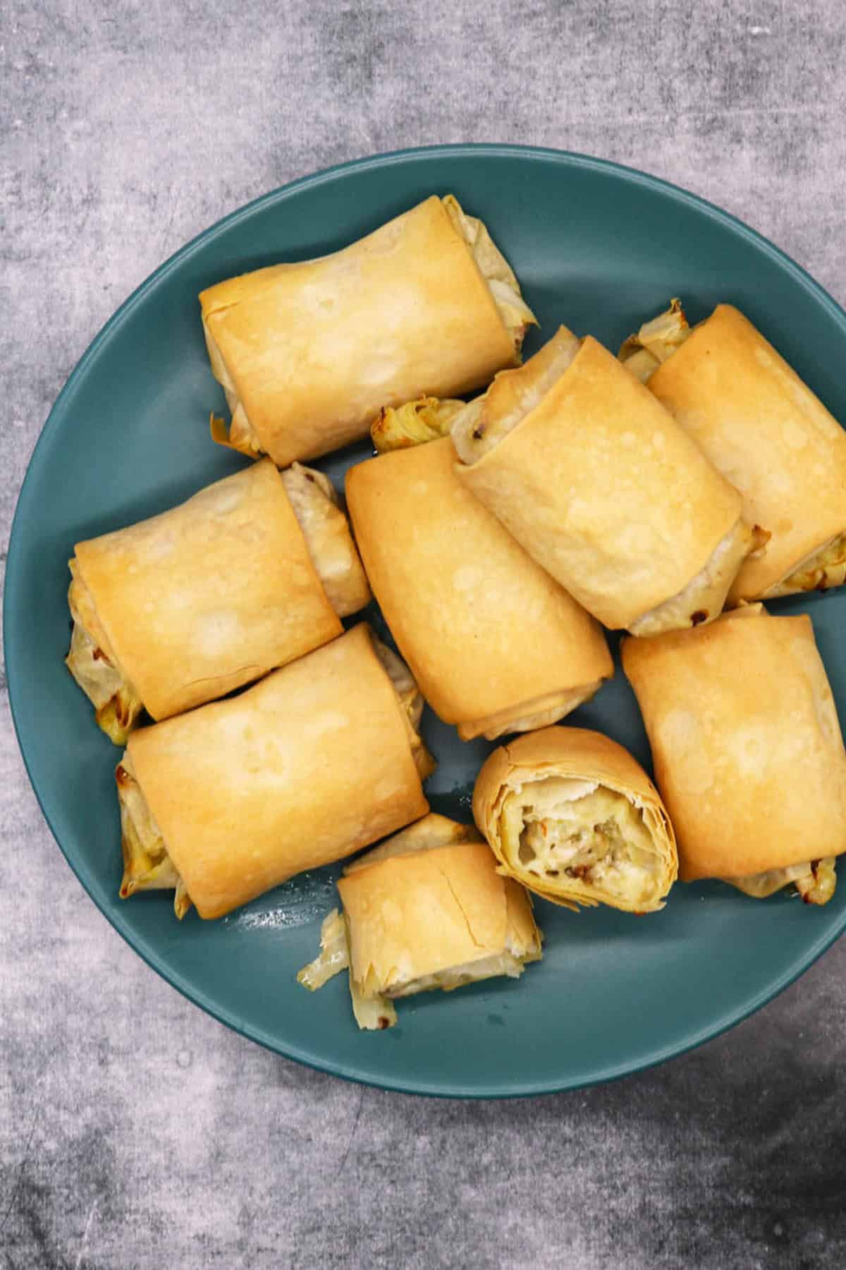 Chicken, mozzarella and pesto filo parcels on a teal dinner plate.