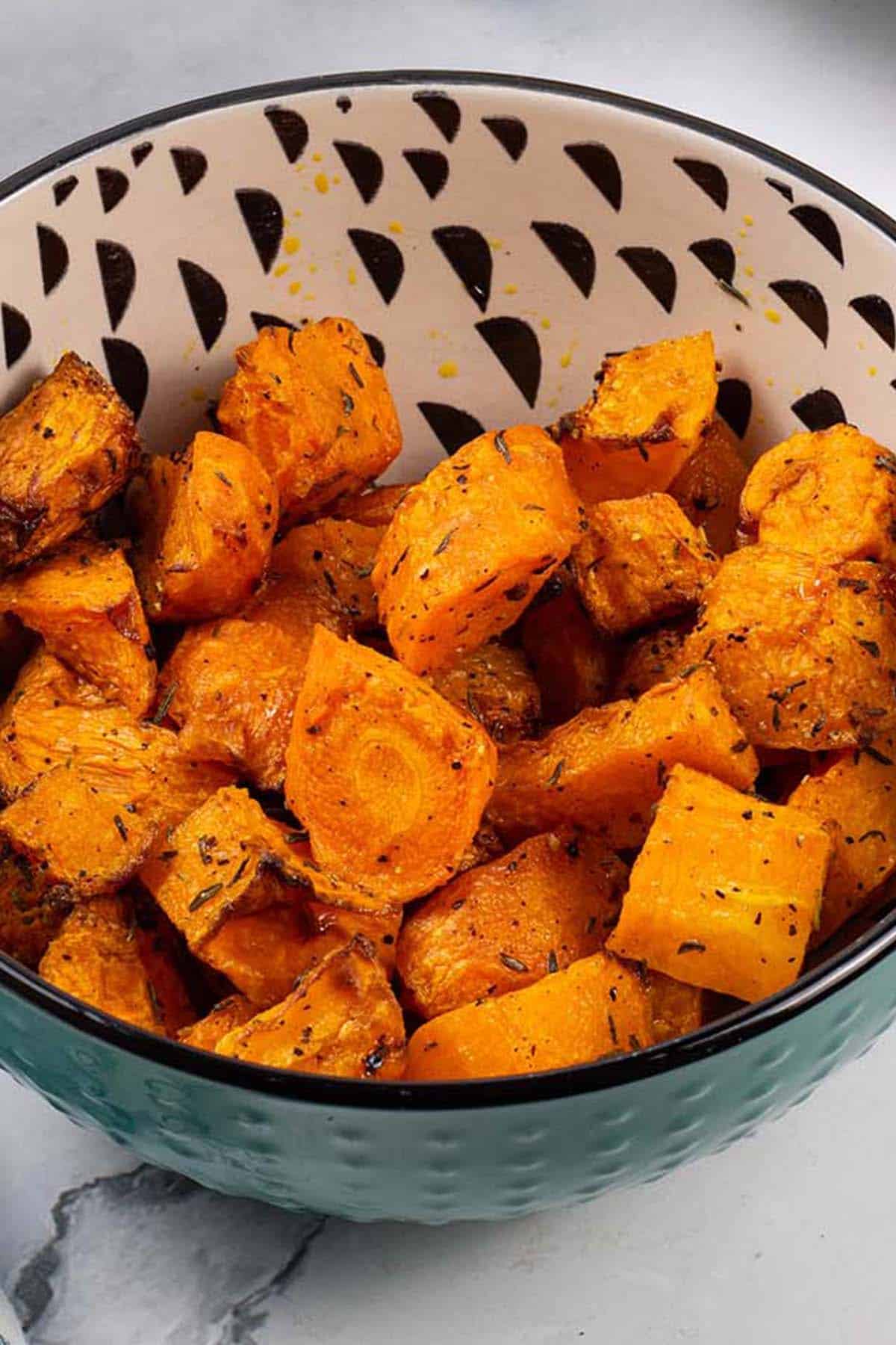 Air fryer carrots and butternut squash in a teal, black and cream patterned bowl.