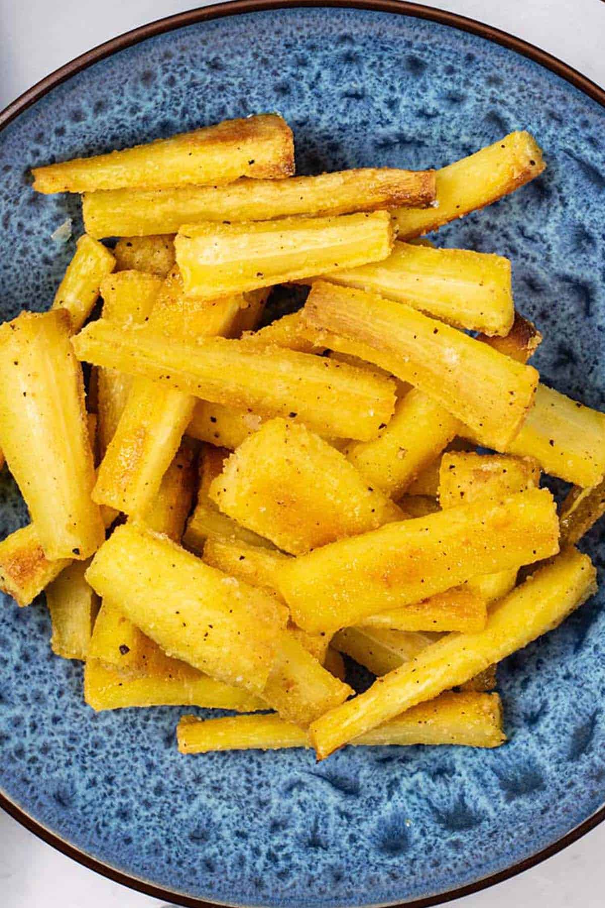 Crisp honey mustard parsnips in a blue patterned serving bowl.