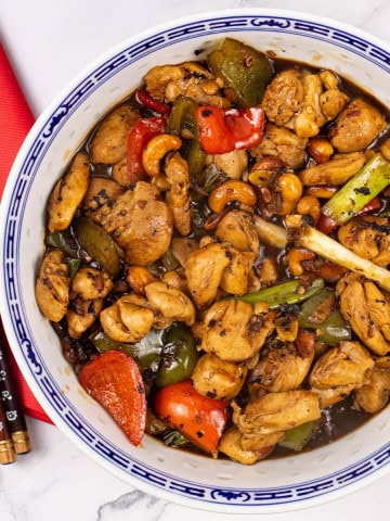 Kung pao chicken in a large blue and white oriental serving bowl.