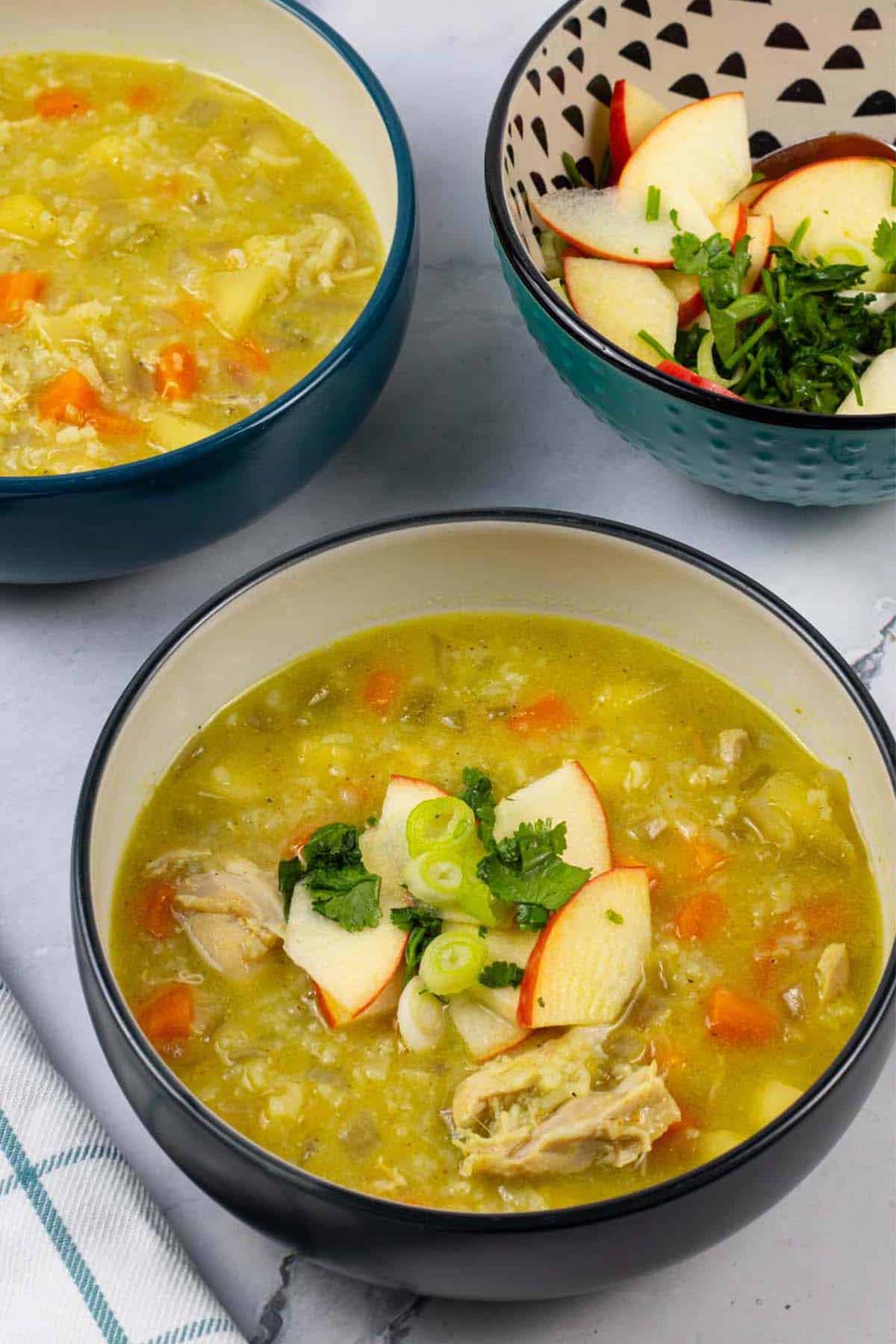 Two bowls of chicken mulligatawny and a bowl of apple relish on the side.
