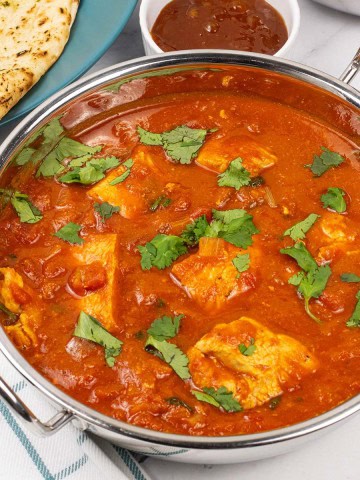 Simple leftover turkey curry in a balti dish with garlic naan and a small dish of mango chutney on the side.