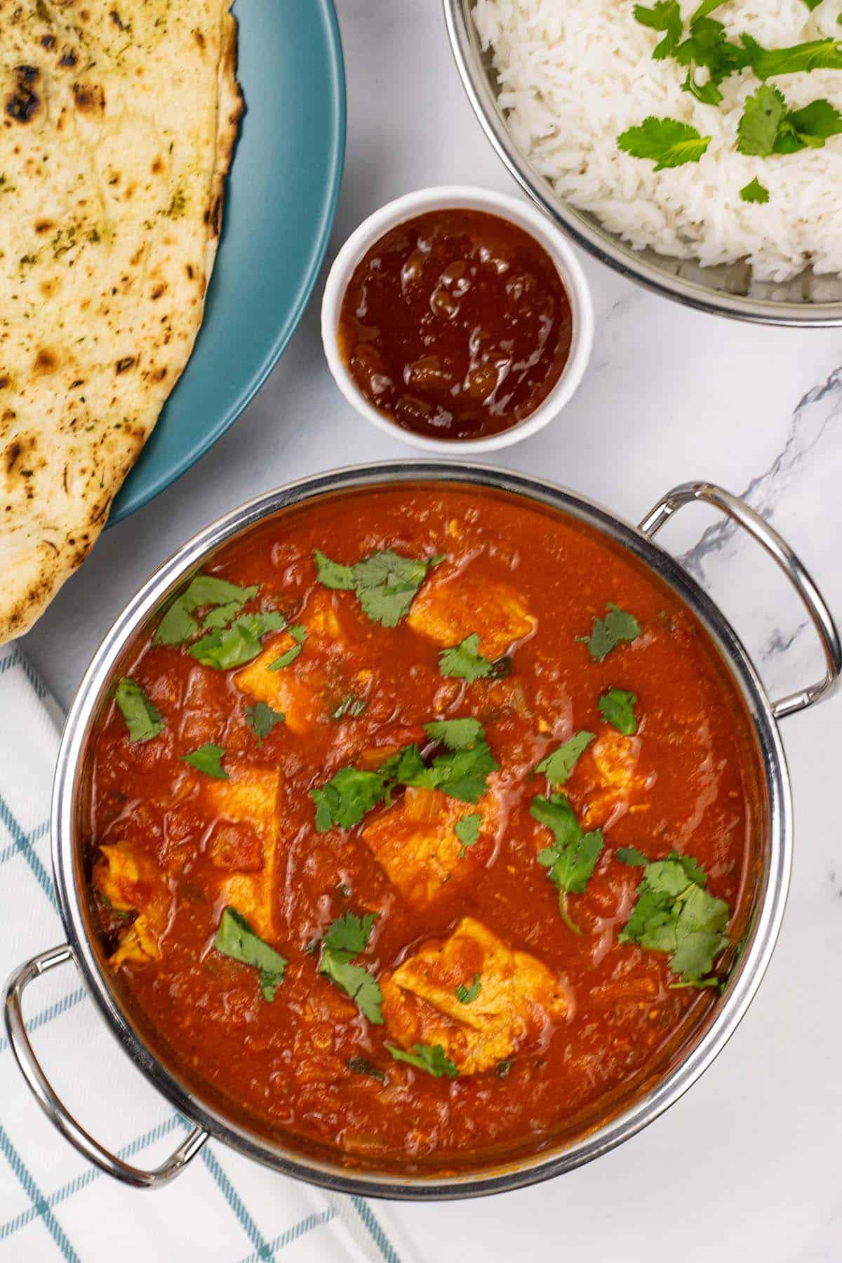 Simple leftover turkey curry in a balti dish with garlic naan, a small dish of mango chutney and a balti dish with basmati rice on the side.