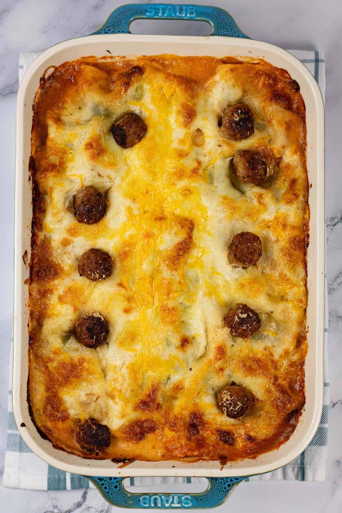 Three cheese meatball lasagne in a large rectangular Staub dish.