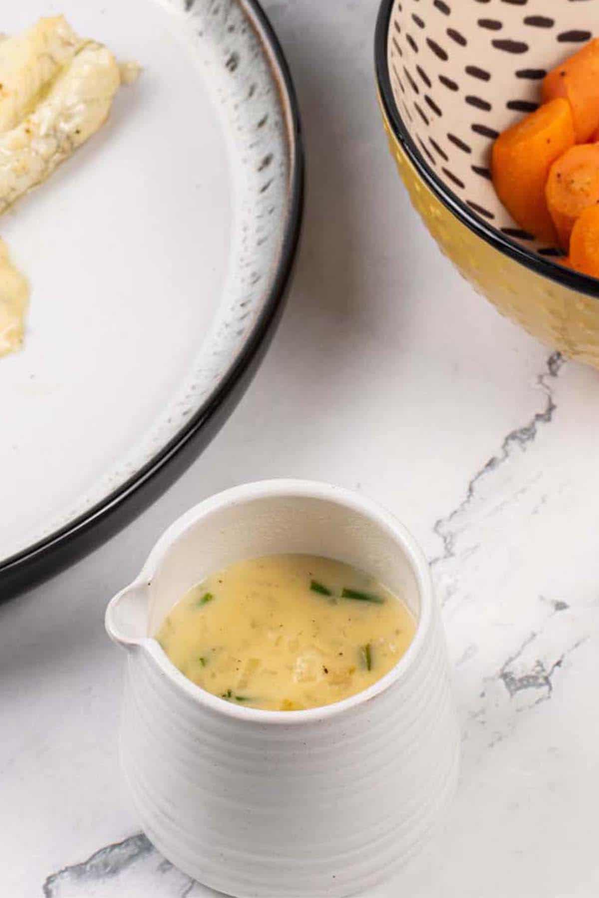 White wine and cream sauce in a small white jug.