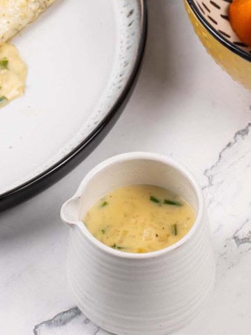 White wine and cream sauce in a small white jug.