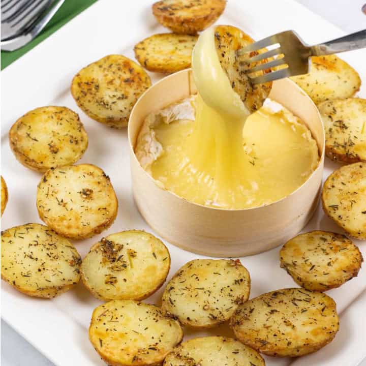 Baked camembert with thyme baby potatoes on a square white platter.