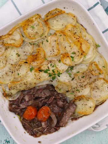 Gressingham duck hot pot in a square oven dish sitting on a green and white towel.
