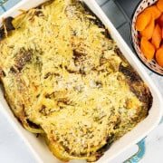 Savoy cabbage gratin with herby cheddar crumbs in a rectangle Staub dish with a bowl of boiled carrots on the side.