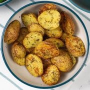 Air fryer thyme roast baby potatoes in a teal and cream serving bowl.
