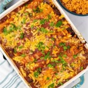 Beef and bean enchiladas in a rectangle Staub ovenproof dish with a bowl of Mexican red rice on the side.