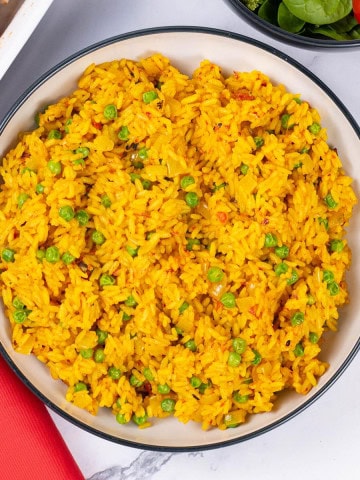 Nando's spicy rice in a black and cream serving bowl.