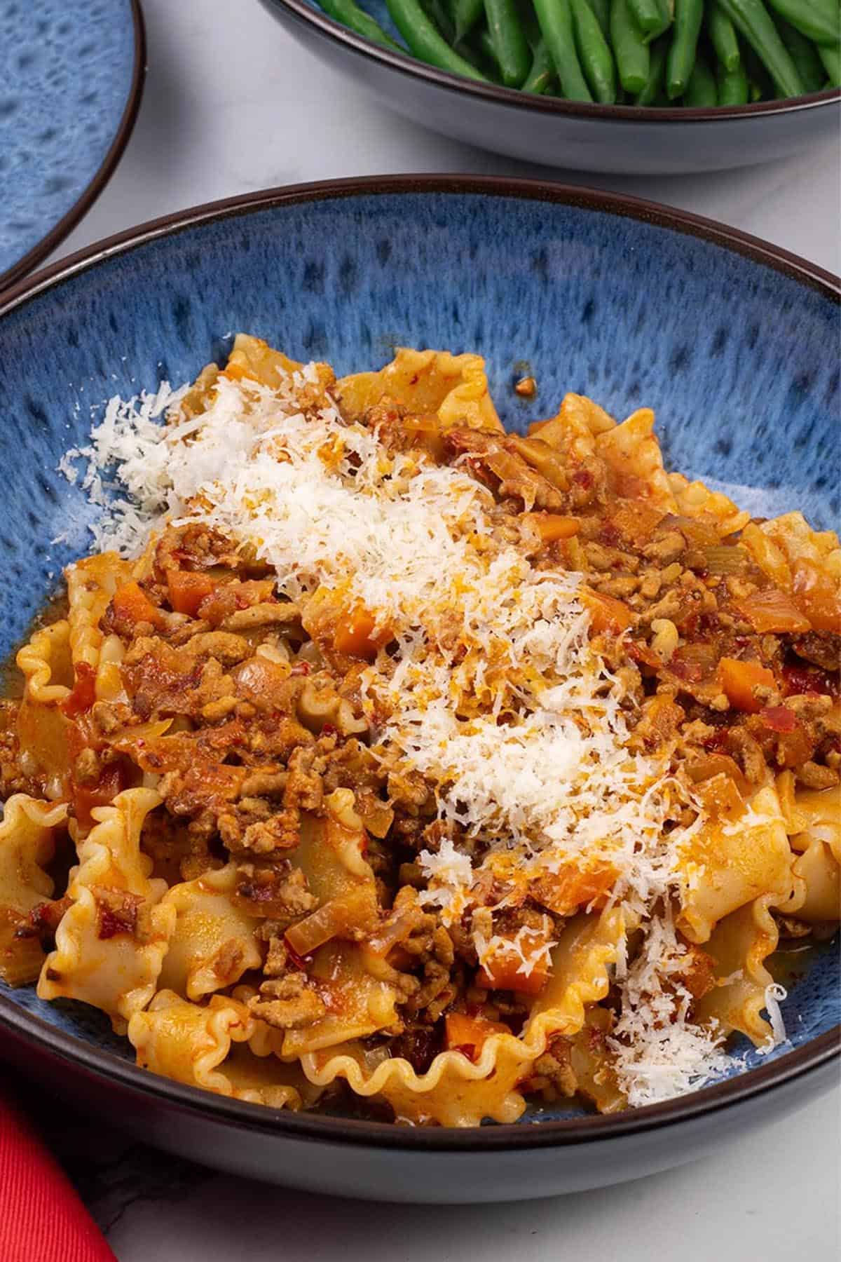 Close up of a portion of 'nduja pasta mafalde in a blue patterned bowl.