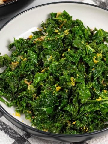 Sautéed kale with chilli and lemon in a black and white serving bowl.