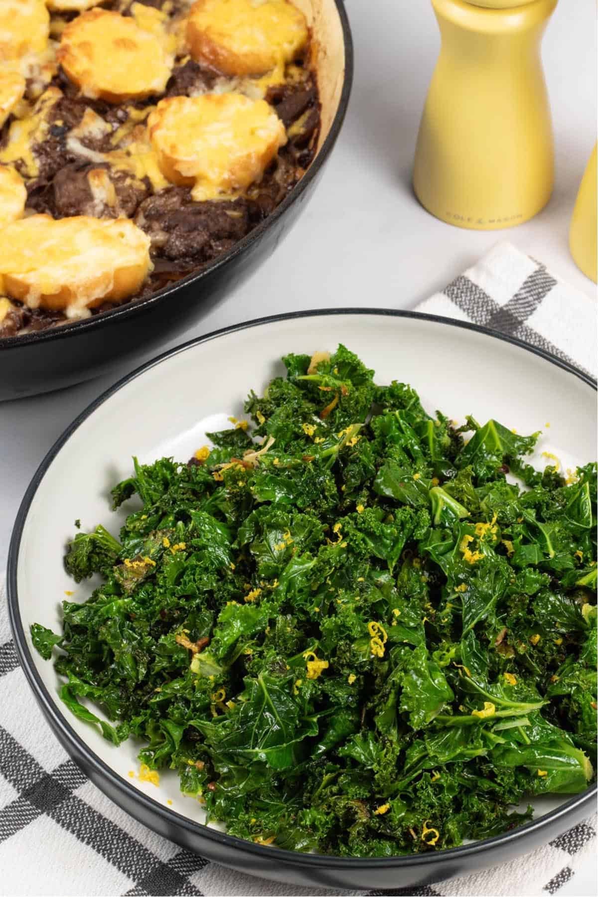 Sautéed kale with chilli and lemon in a black and white serving bowl.