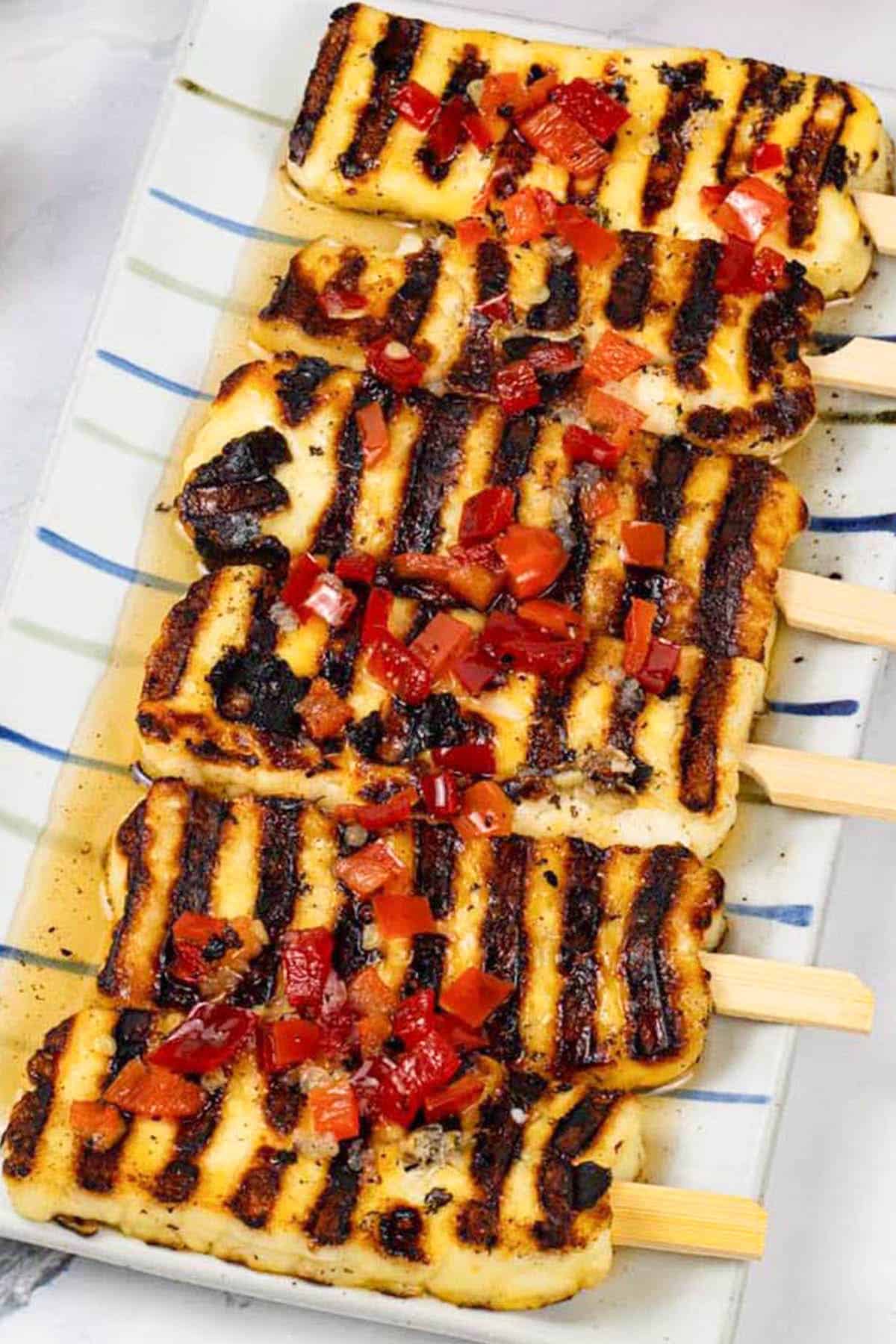 Sweet chilli halloumi skewers on a striped platter.