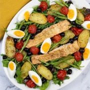 Easy salmon nicoise traybake on a white serving platter with a mustard napkin on the side.