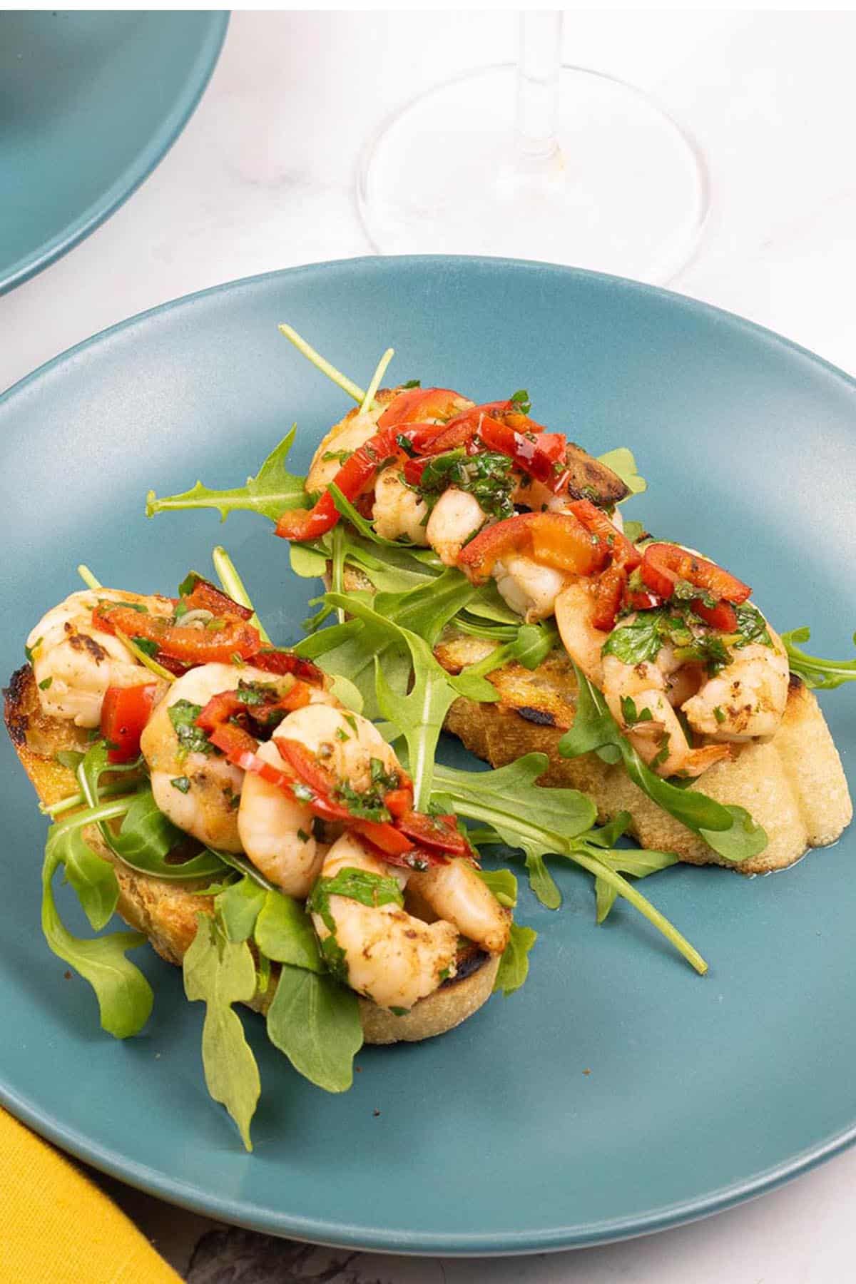 A portion of lemony prawn bruschetta on a teal side plate.