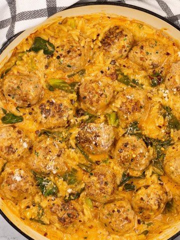 Marry me chicken meatball orzo in a large shallow casserole dish, with a black and white checked towel on the side.