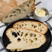Portuguese water bread made in the Thermomix on a black and white checked towel, with a couple of slices on a black side plate.