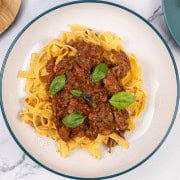 A portion of slow cooker beef ragu in a pasta bowl with tagliatelle.