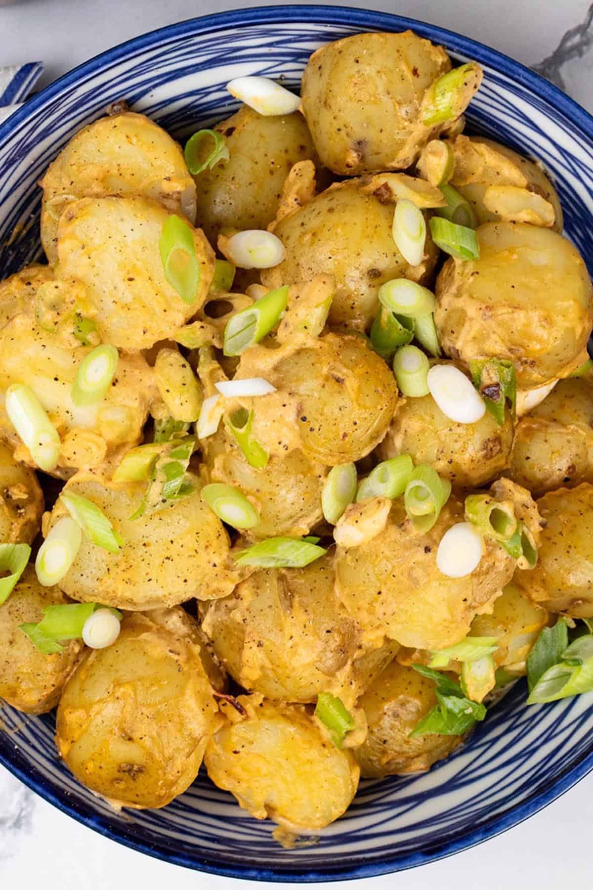 Close up of smoky chipotle potato salad in a blue and white serving bowl.