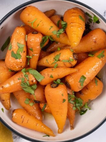 Easy sweet roasted chantenay carrots in a black and white serving bowl.