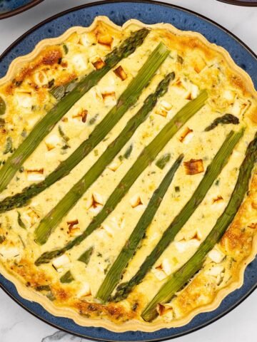 Spring vegetable and feta quiche on a blue patterned dinner plate.