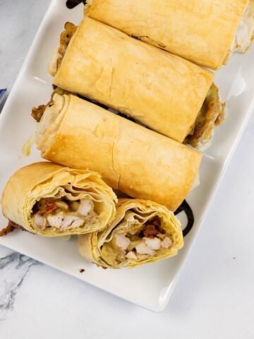 Chicken, mozzarella and pesto filo parcels on a white rectangular serving platter.