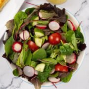 Easy baby leaf salad in a light blue rimmed serving bowl.