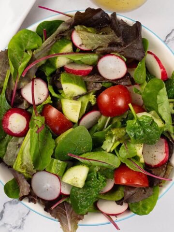 Easy baby leaf salad in a light blue rimmed serving bowl.